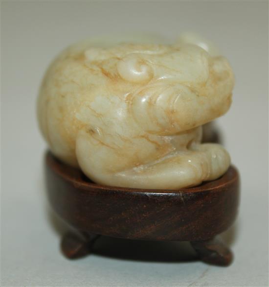 A Chinese pale celadon and russet jade recumbent figure of a bixi, 19th century, 5cm, wood stand